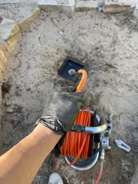 Plumber feeding a jetting hose into an underground drain