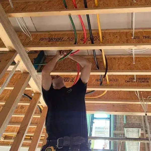 Plumber running pipework through the ceiling frame of a new build